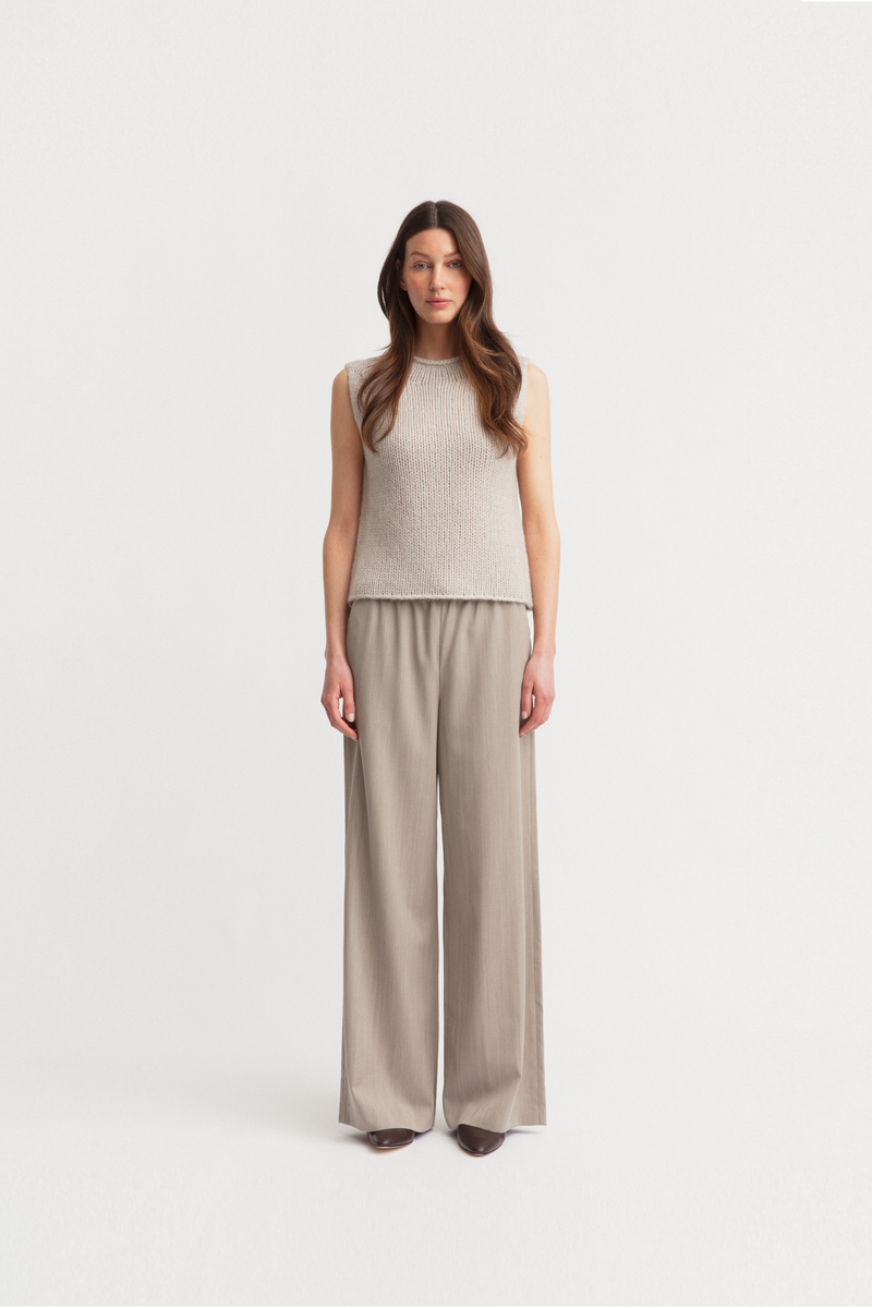 Model  wearing a sleeveless ribbed knit top and matching wide-leg trousers in a light taupe-beige color from iris Von Arnim.
