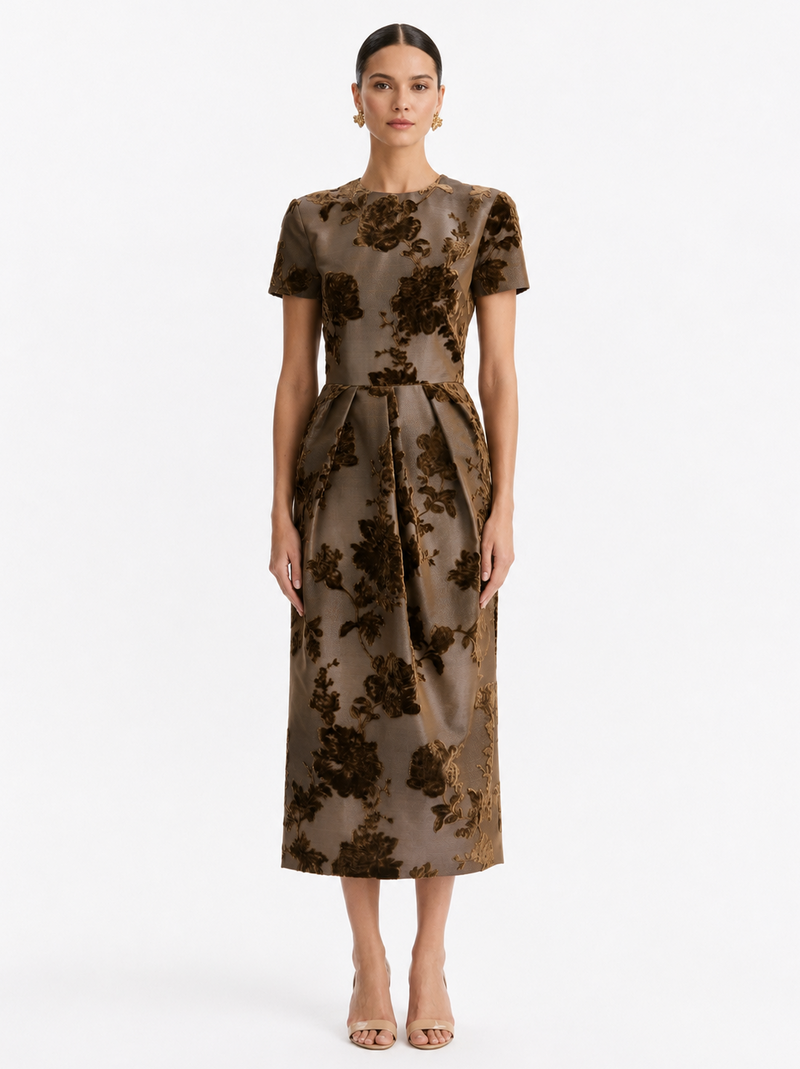 A woman modeling a short-sleeved midi dress with a brown and bronze floral jacquard pattern, from Oscar de la Renta. 