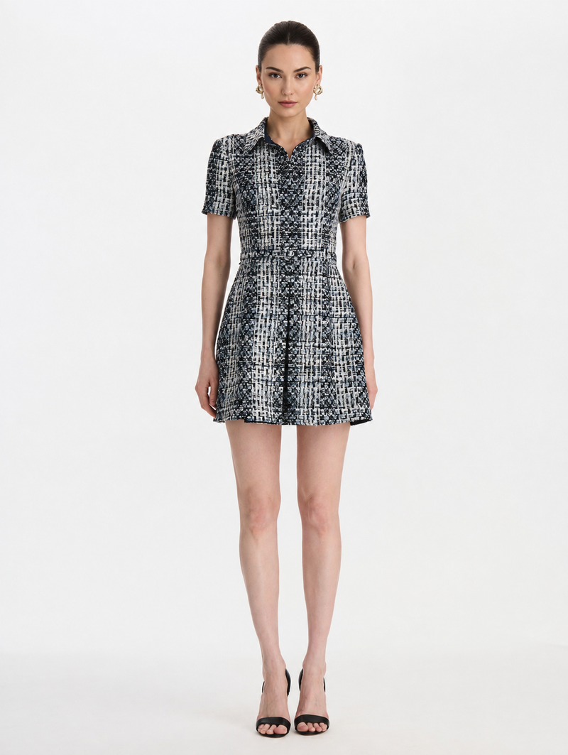 A woman modeling a short-sleeve collared mini dress with a black and white geometric pattern, by Oscar de la Renta. 