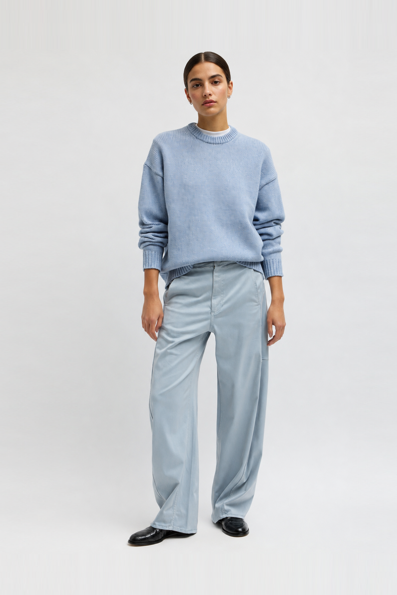 A model in a light blue knit crewneck sweater and matching wide-leg trousers by Tibi. 